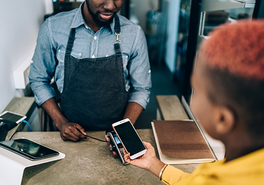 A person making a payment with his cellphone via the tap option on a credit card machine