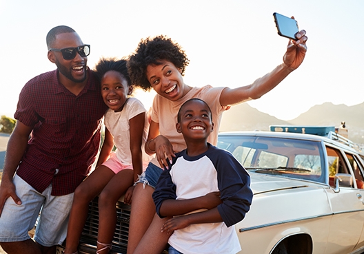 young family taking a selfie on the bonnet of their car