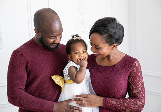 parents holding their daughter smiling down at her