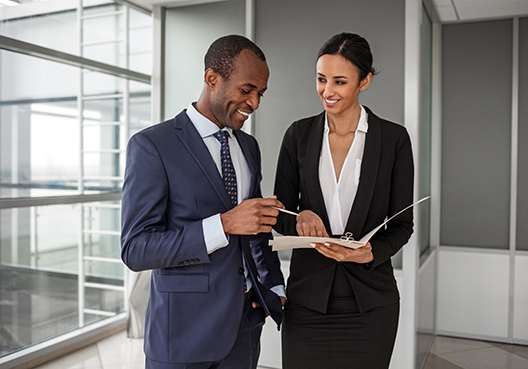 two colleagues talking while looking at a folder