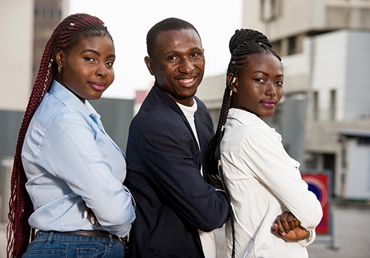 Three colleagues standing shoulder to shoulder smiling at the camera