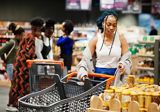 Woman standing in a supermarket with a trolley looking at groceries