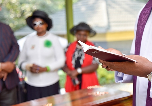 pastor standing over a coffin with a bible