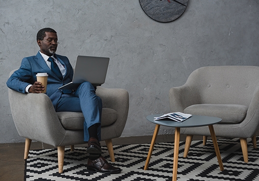 man sitting on an armchair with his laptop on his lap