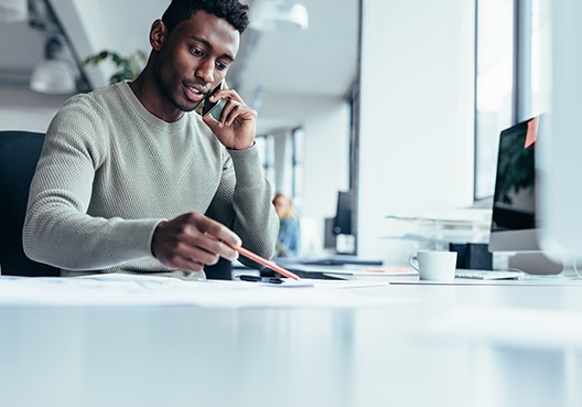 A man talking on his cellphone at his desk