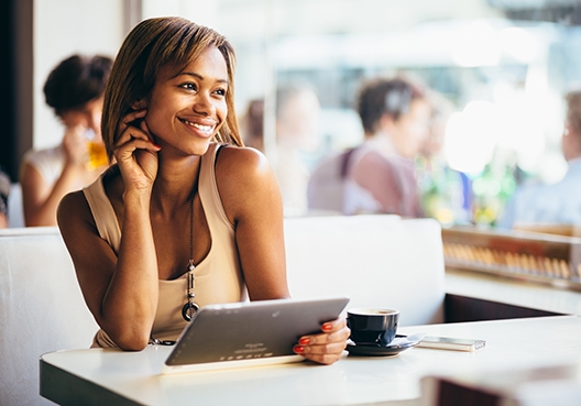 woman sitting at a table with a phone tablet in her hand