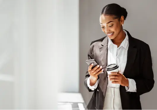 Lady standing in office, drinking coffee to go and using cellphone