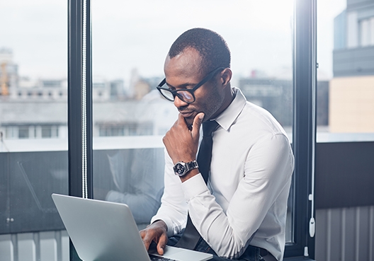 A man sitting deep in thought while staring at his laptop