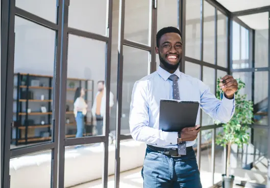 Joyful black male real estate agent smiling cheerfully carrying notebook 