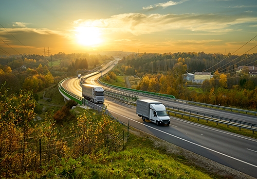 Two trucks driving on a long stretch of road