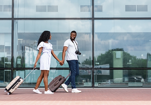 couple walking at the airport with their luggage