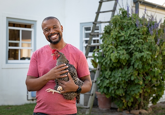 man standing in front of his house holding a chicken