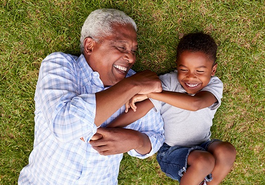 granddad and grandchild lying on the grass